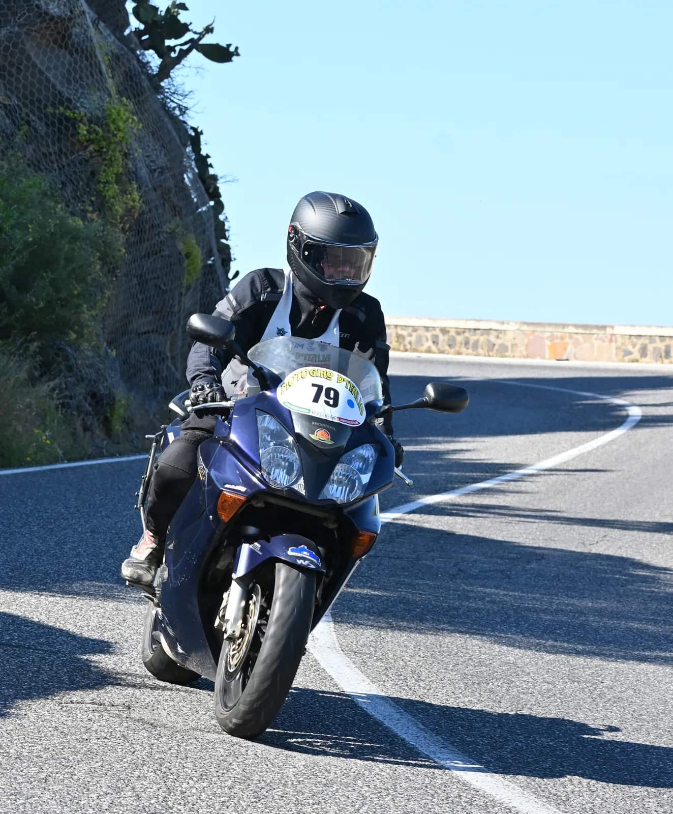 Partecipante del Motogiro d'Italia in curva su una strada costiera