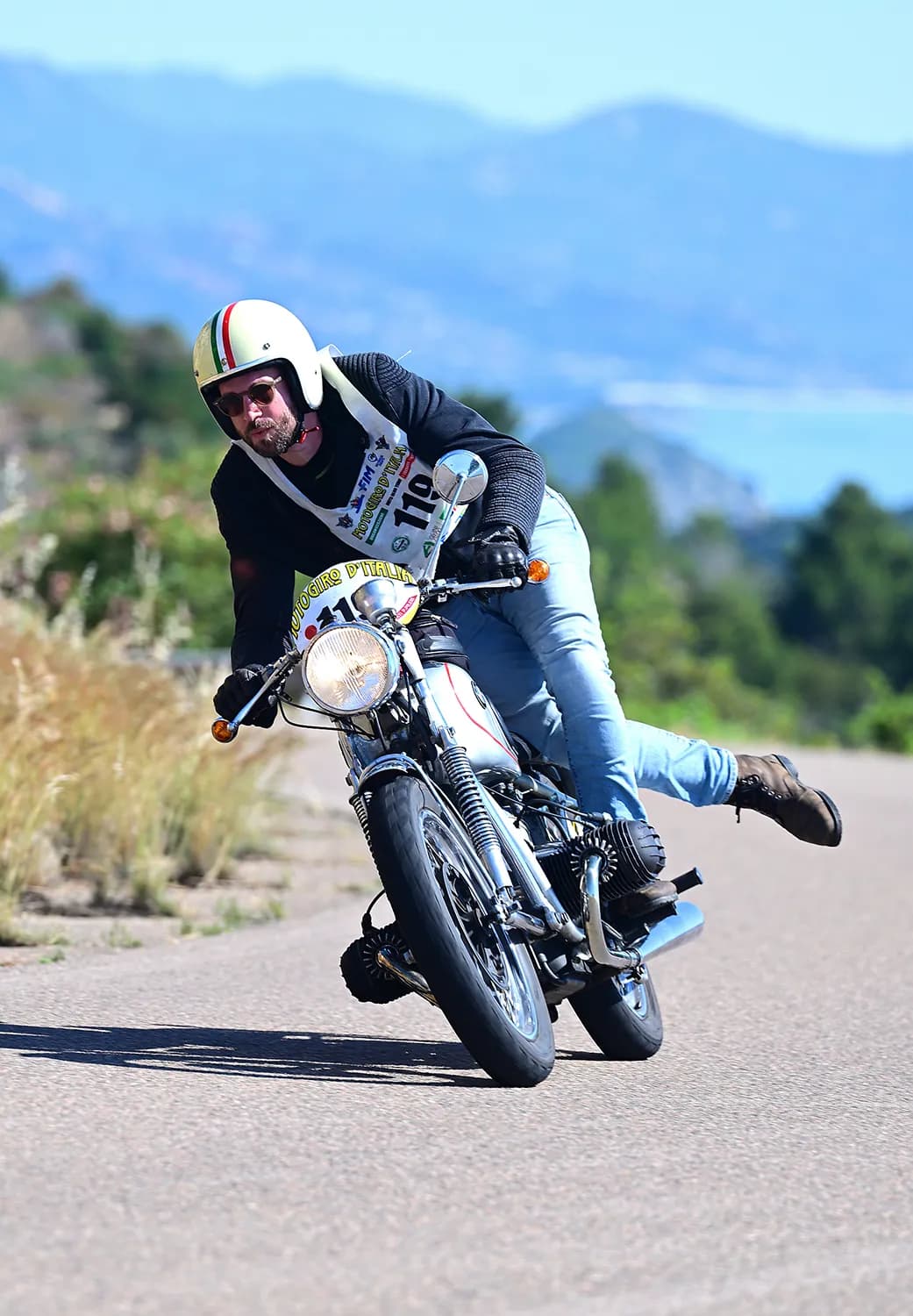 Motociclista saluta con la mano durante la tappa