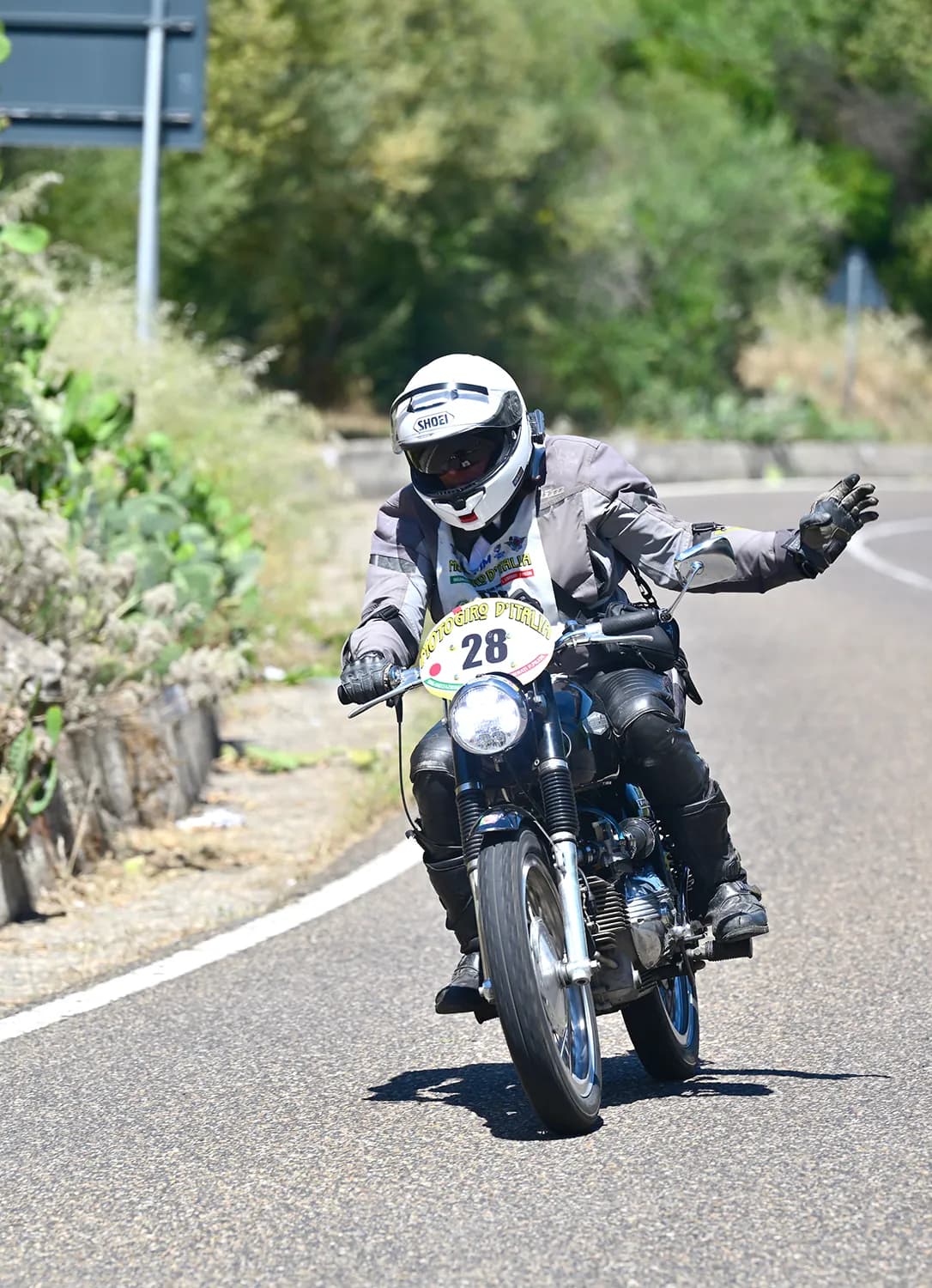 Motociclista in curva con paesaggio verde alle spalle